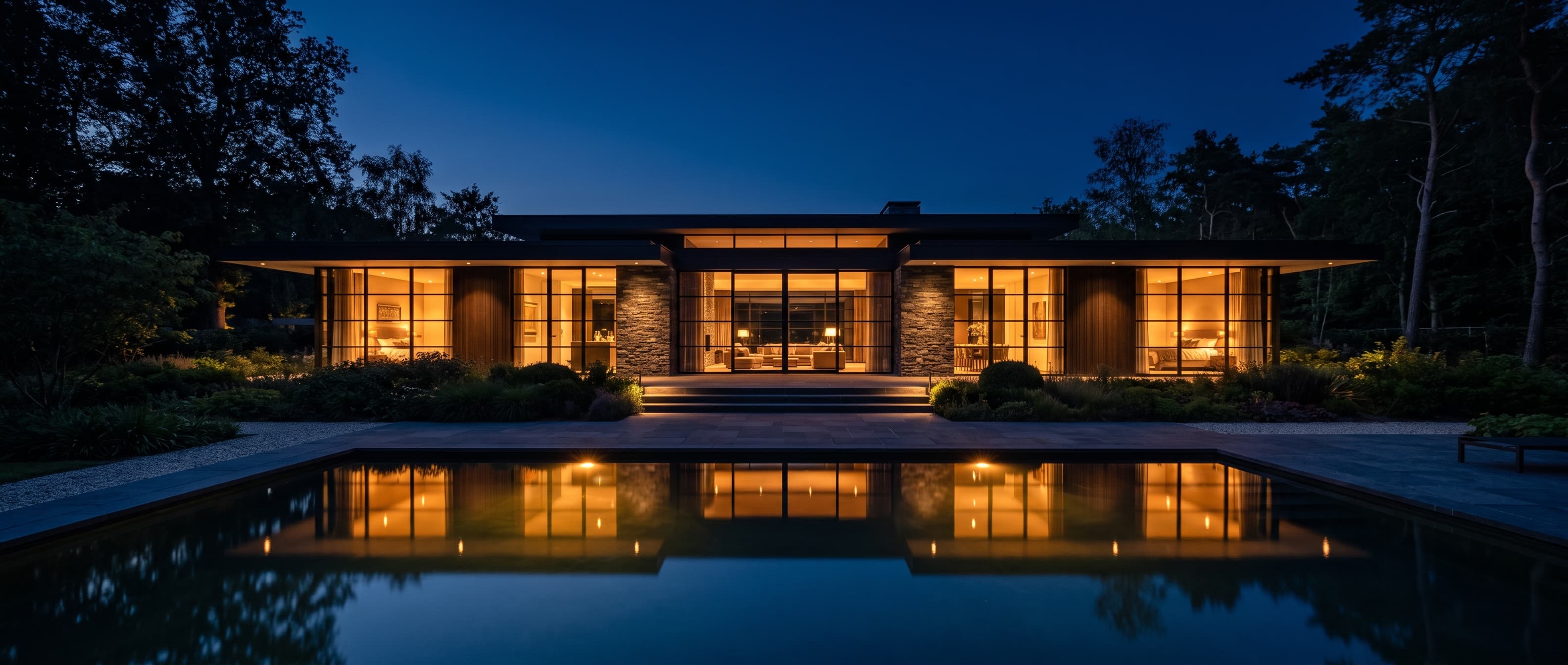 Modern house at night with warm light glowing through large glass walls