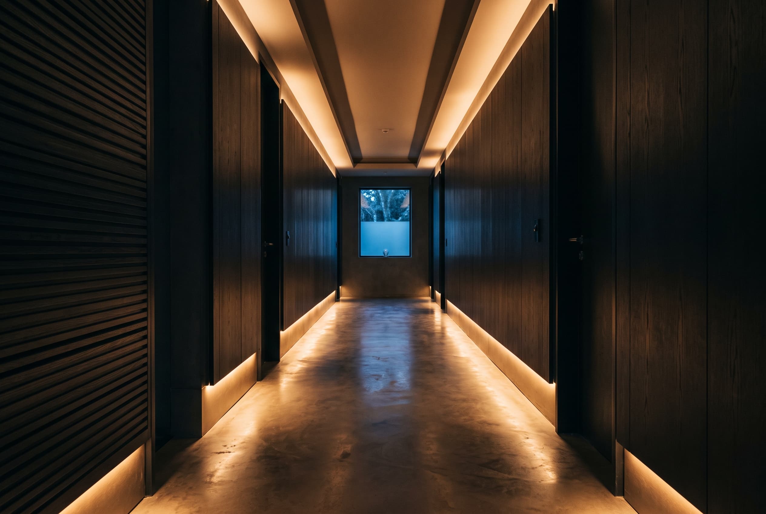Minimal hallway at night lit by continuous warm cove lighting